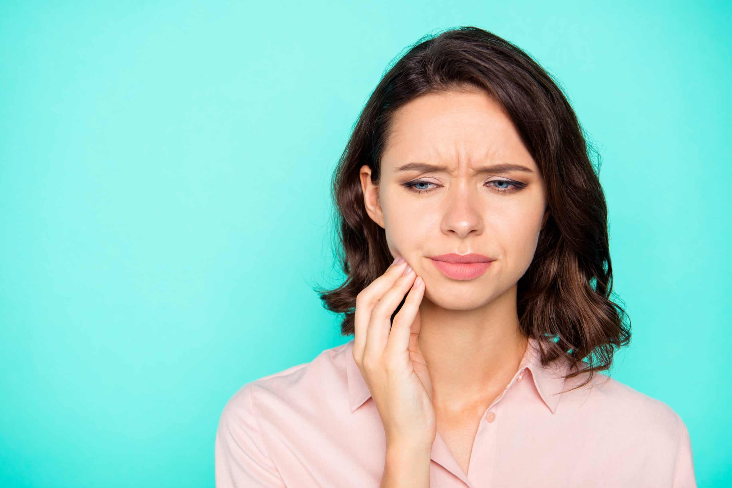 Close-up portrait of nice attractive sad unhealthy lady touching cheek copy empty blank space isolated over turquoise teal pastel background