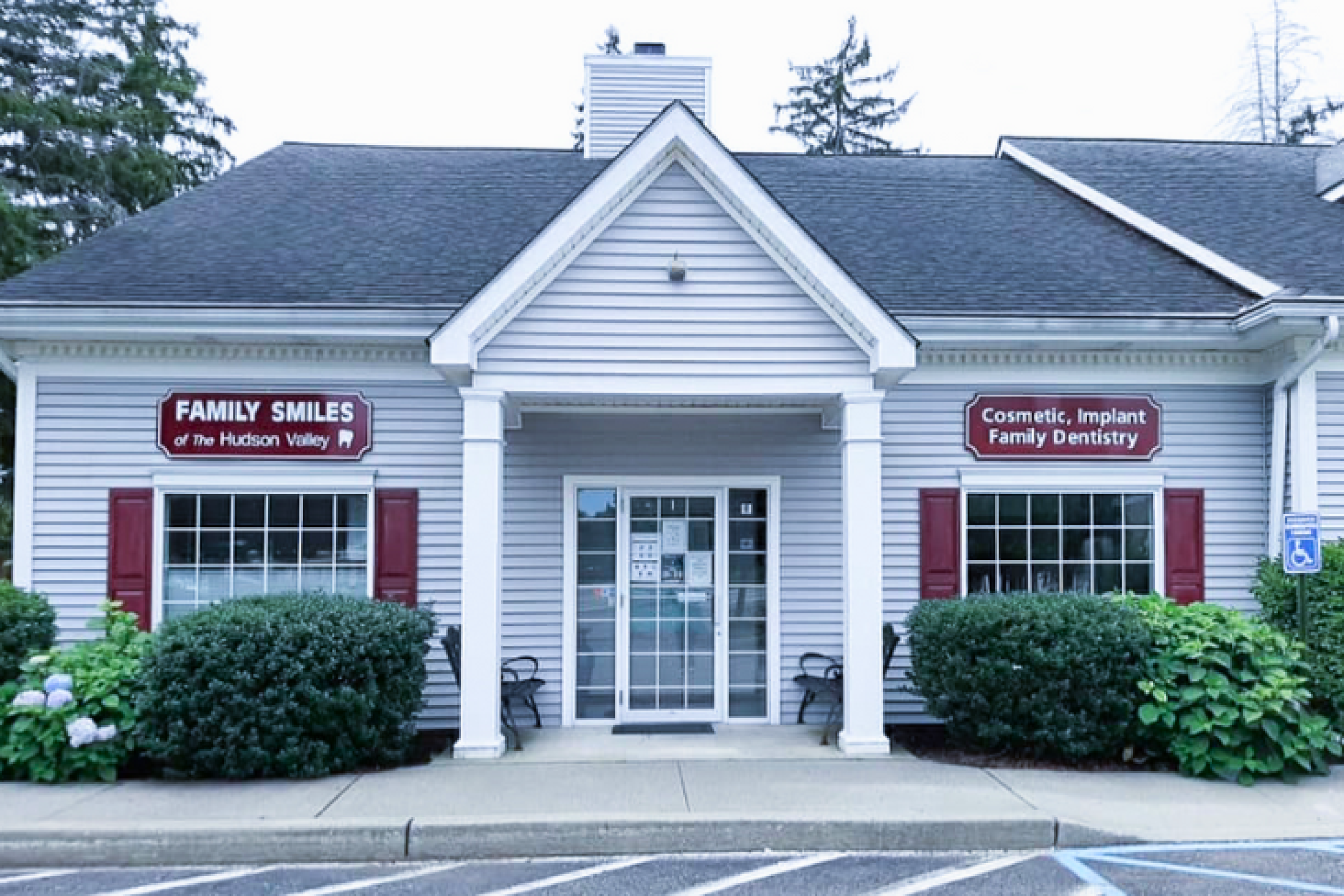 The exterior of Family Smiles of The Hudson Valley dental clinic featuring signs for cosmetic and implant dentistry.