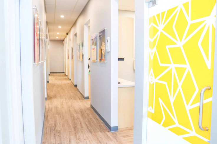 Bright dental clinic hallway with modern decor and a geometric yellow door design.