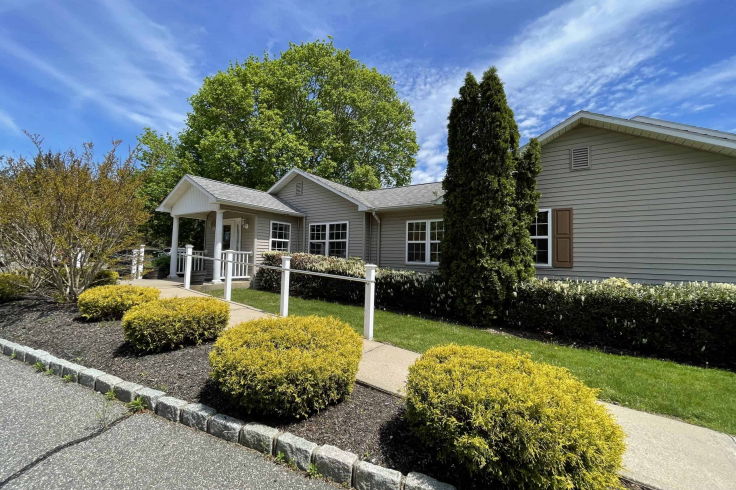 The exterior view of a dental clinic with a garden and pathway leading to the entrance.