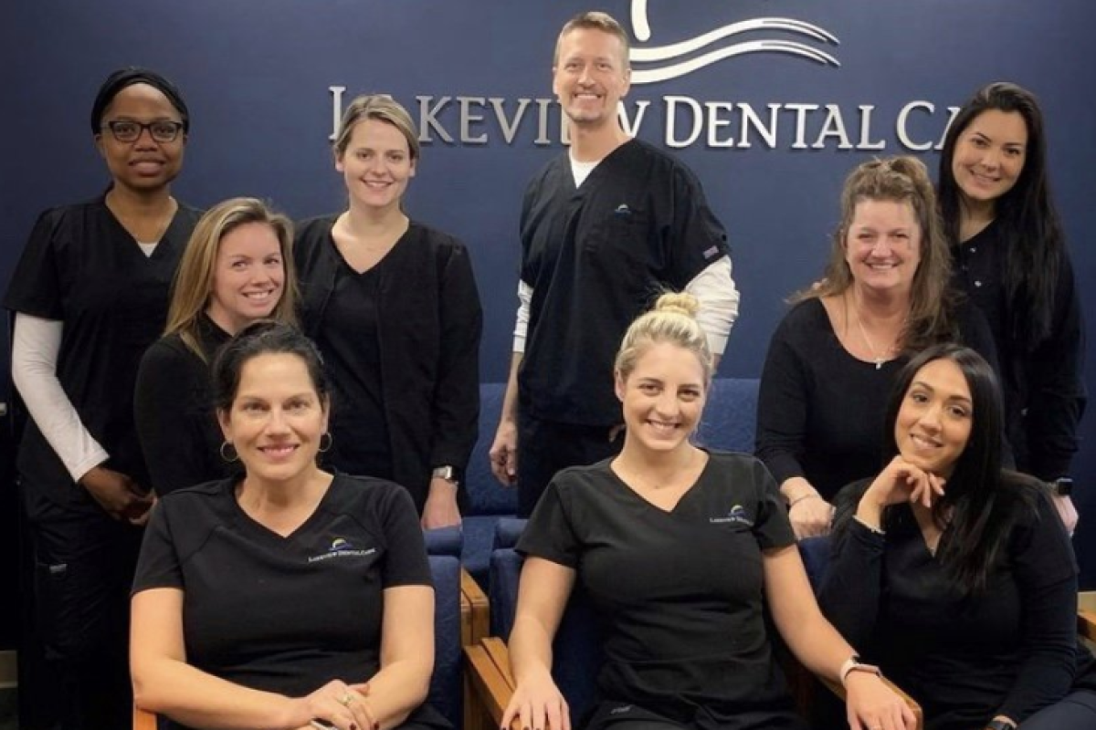 A group of dental professionals in black uniforms smiling in front of a wall with the "Lakeview Dental Care" logo.