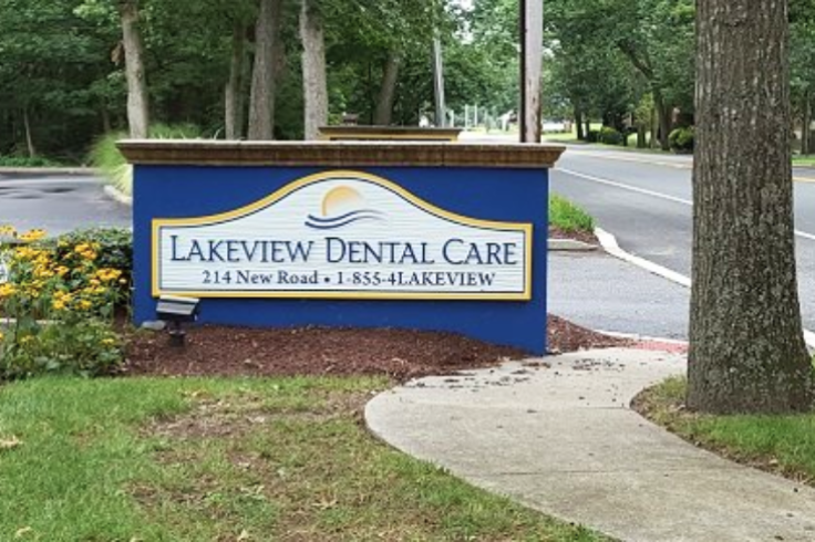 Sign for Lakeview Dental Care featuring contact information at the road entrance surrounded by greenery.