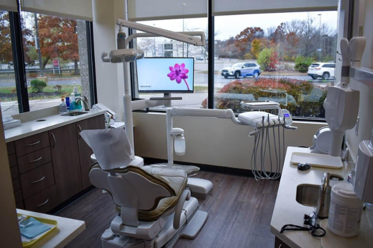 Modern dental office interior with dental chair, equipment, and a window view of the street outside.